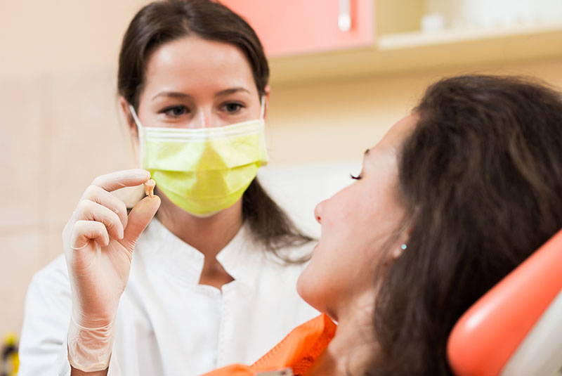 dentist showing patient extracted tooth