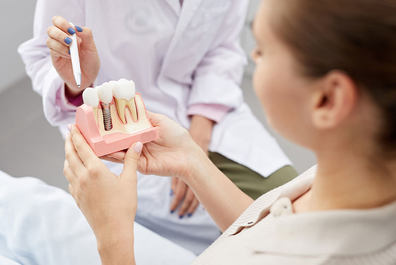 dentist showing patient a dental implant model