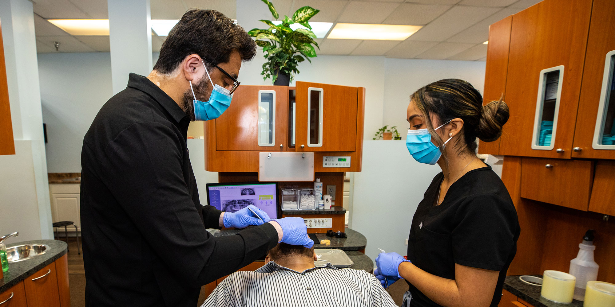 Dr. Asim performing dental procedure on patient